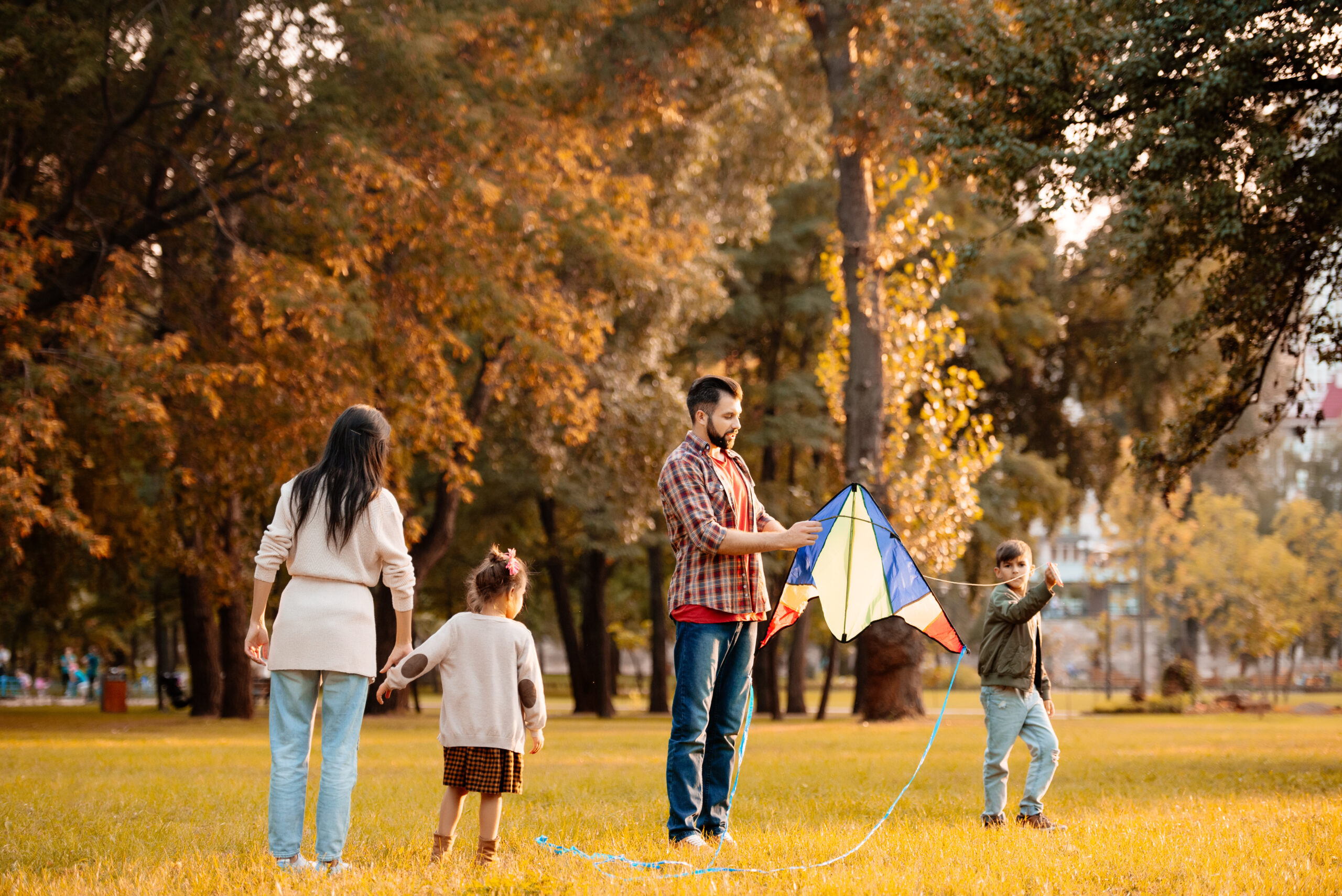 Family with children trying to fly a kite in an autumn park